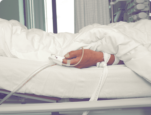 Patient's hand with IV on hospital bed.