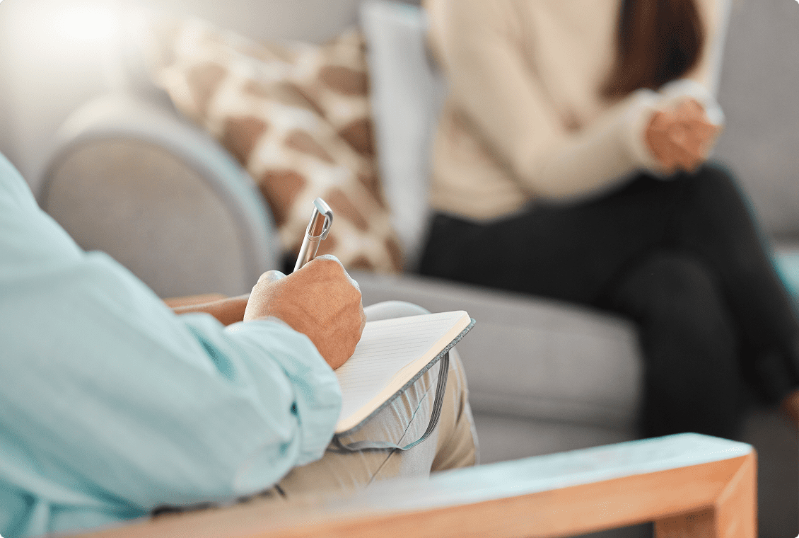 Therapist taking notes during a counseling session.
